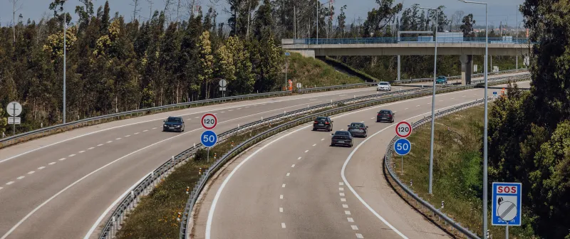 Curving motorway with speed limit signs and an SOS point
