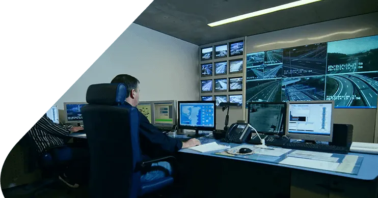Centro de controlo de tráfego com operadores e uma parede de ecrãs com imagens das autoestradas